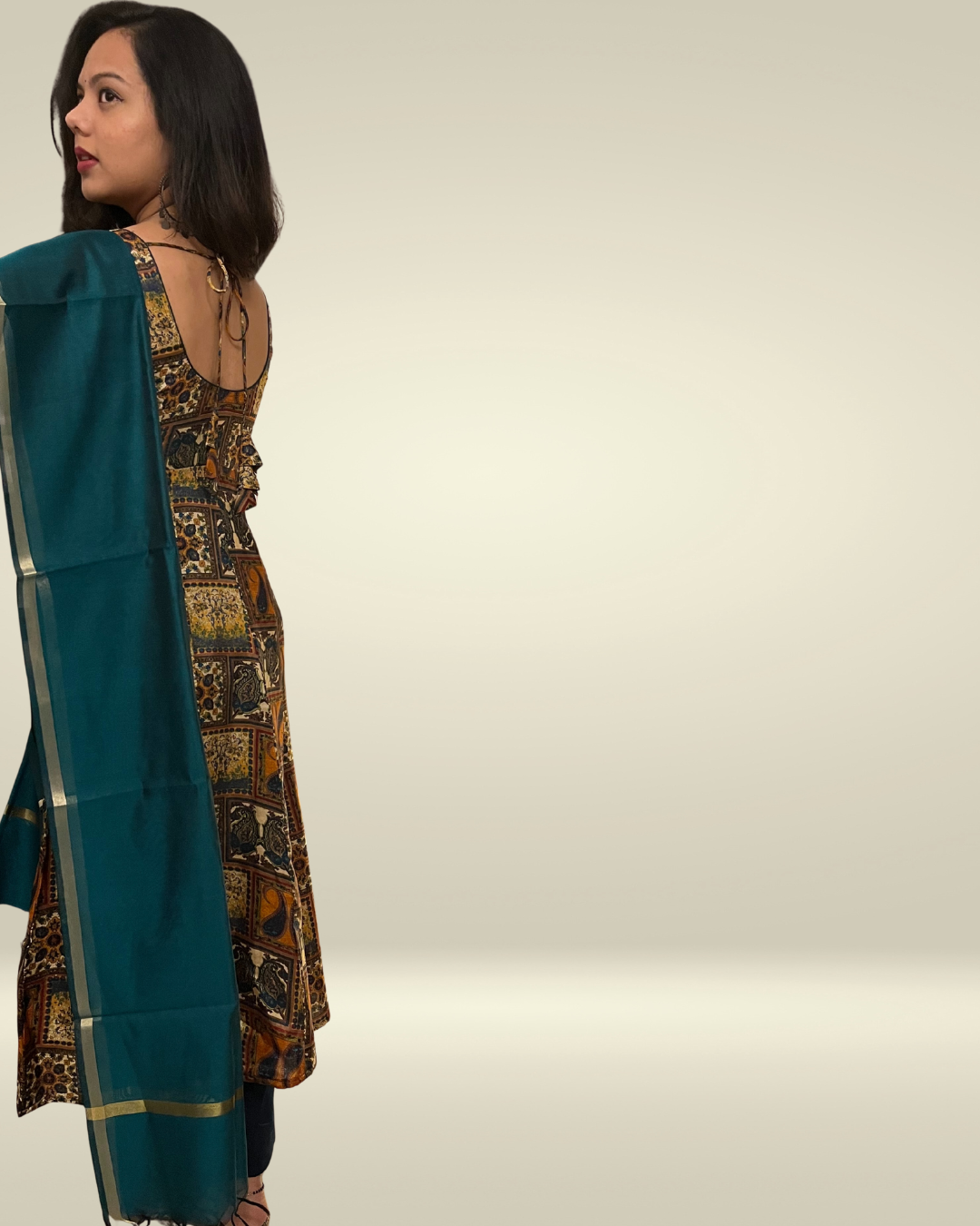Woman wearing a teal saree with a patterned blouse against a neutral background